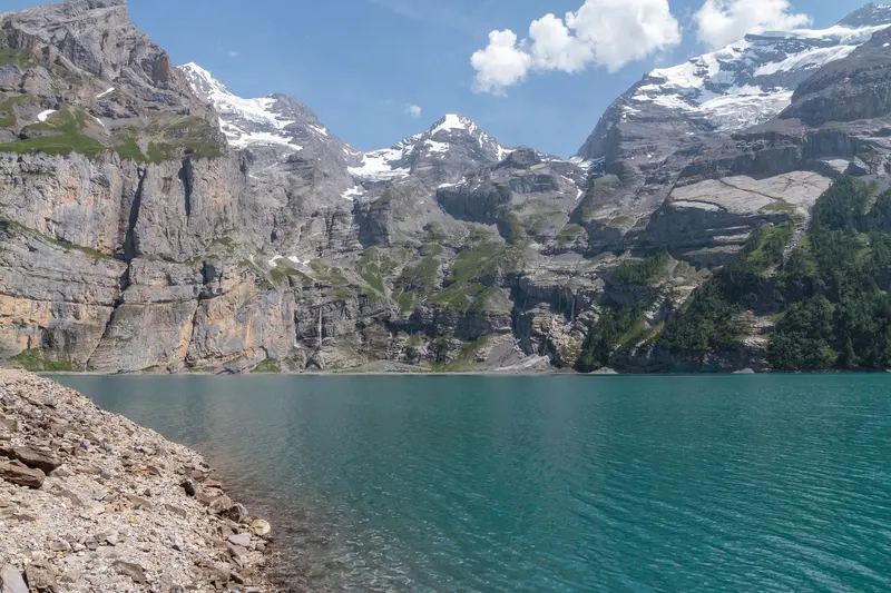 Der türkisfarbene Oeschinensee unter Kalkwänden und verschneiten Gipfeln